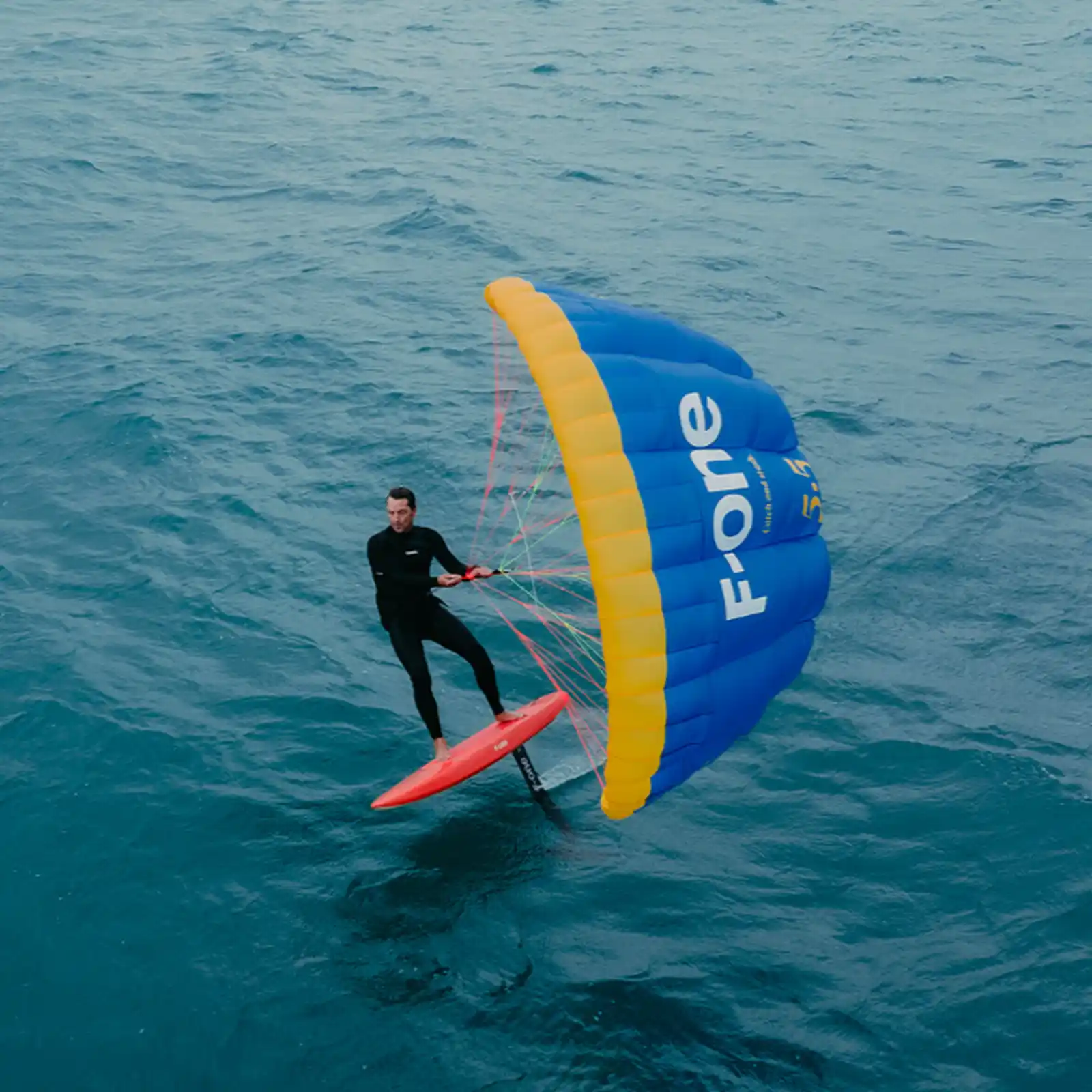 Rider en plein saut avec la Slingshot Flowcraft V2 et la wing NXT, démonstration de contrôle et de lift au-dessus de l’eau.